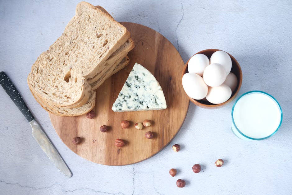 Top view of a classic food arrangement on a wooden board featuring bread, blue cheese, eggs, and milk.
